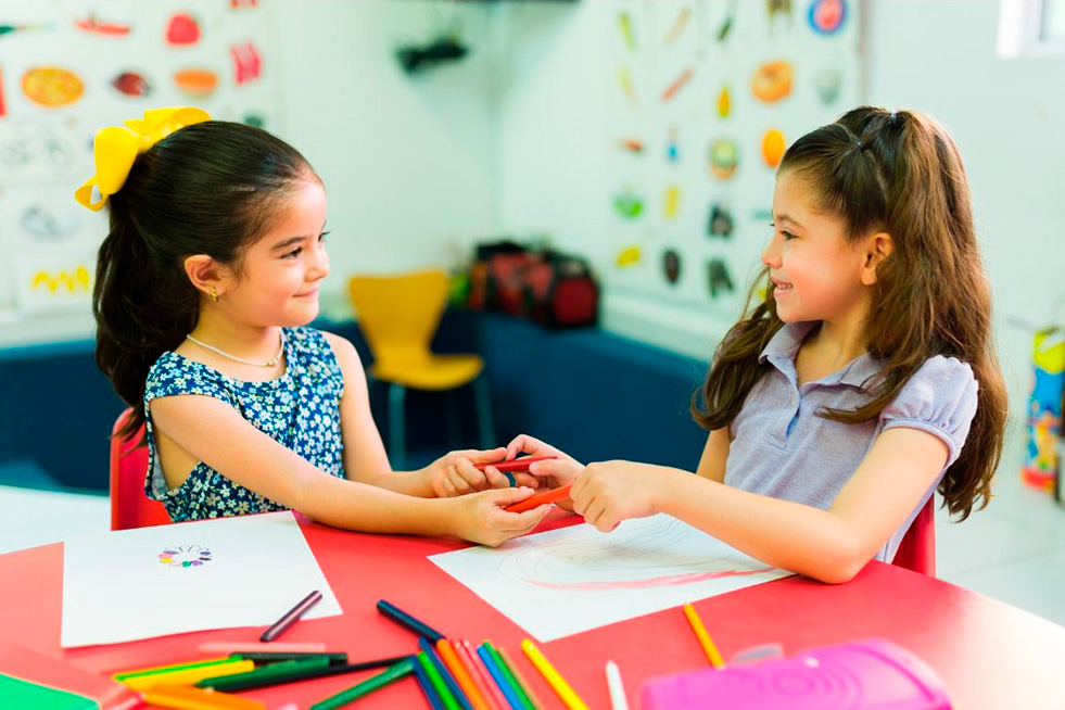 Two girls engage in a fun activity at a colorful table, sharing and playing with crafts while showcasing their friendship.